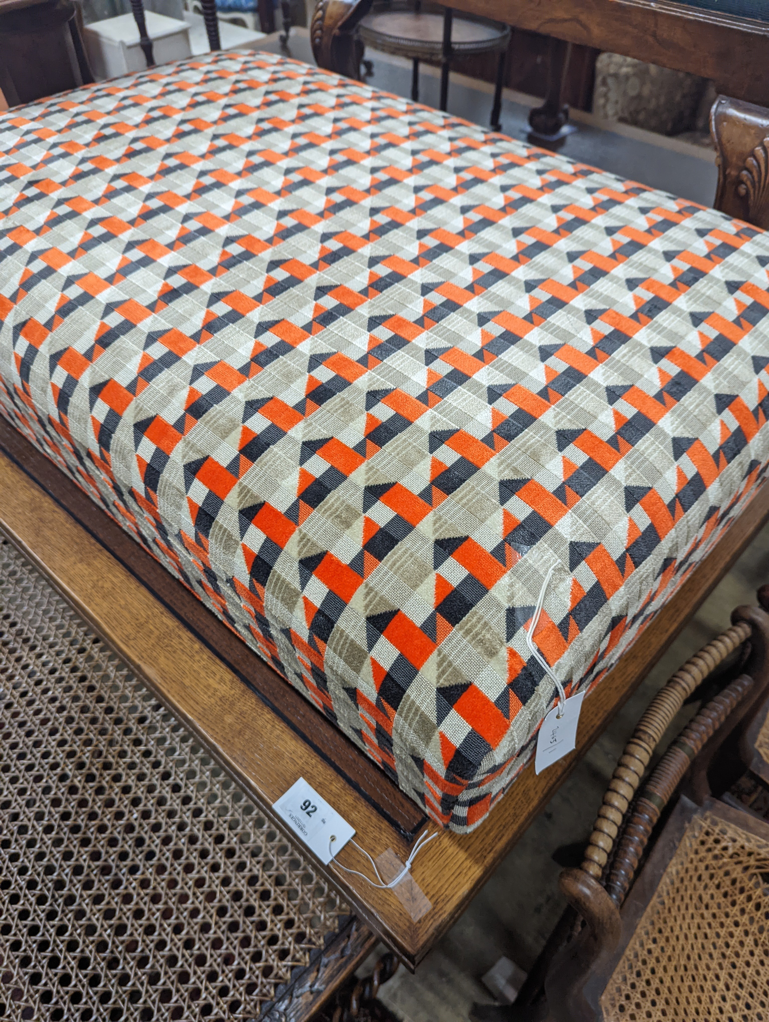 A contemporary rectangular footstool upholstered in Romo 